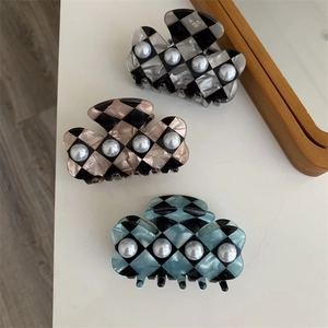 Close-up of checkerboard hair claws in three colors with pearl accents and acetate finish