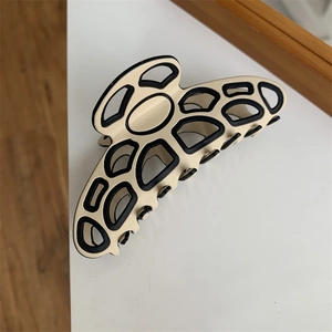 Detailed close-up of a hollow butterfly hair claw clip with contrast black piping