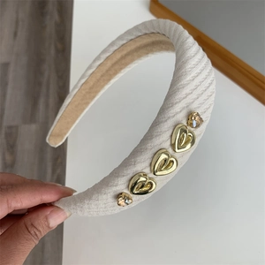Close-up of beige woven headband featuring golden hearts and amber crystal details