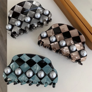 Detail of checkered acetate hair claws featuring pearl embellishments in various colors