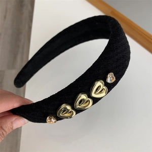Detail of black thick knitted headband featuring gold heart charms and amber crystals