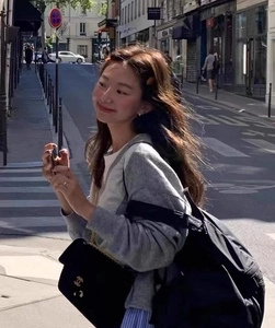 Street style shot of a woman wearing the elegant black velvet chain bag with metal logo