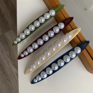 Detail of four colorful hair claws with gradient pearls and Barrette La France text
