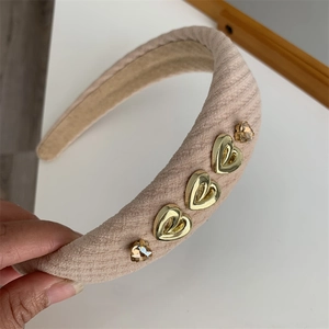 Detail of a padded pink headband with knit texture, gold hearts, and brown rhinestones