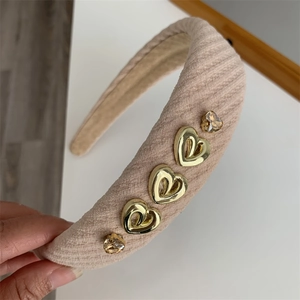Detail of pink corduroy headband with golden heart metal charms and amber rhinestones