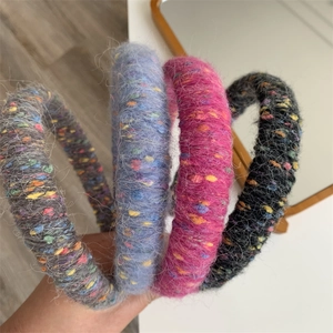 Detail showing soft knitted plush texture of various rainbow hairbands in hand
