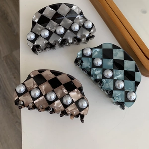 Macro shot of checkered pattern hair claws with pearl accents in three distinct colors