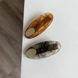 Close-up of elegant amber and grey translucent resin hair clips with gold metal plates