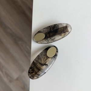 Detail view of oval hair clips with black smoke resin and golden metal accents