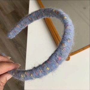 Detailed close-up of light blue knitted headband with colorful fiber dots and plush texture