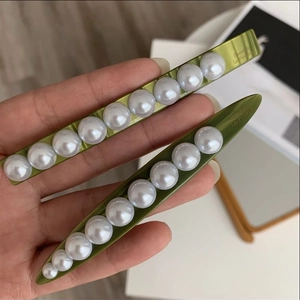 Detailed close-up of green acetate hair clips with white pearls and Barrette La France text