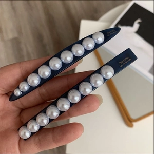 Close-up of navy blue pearl hair clips with Barrette La France gold lettering detail