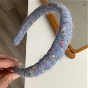Close-up of fog blue knitted headband with colorful speckled yarn and fuzzy mohair texture