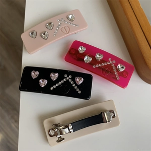 Detail of four acrylic rectangular hair clips with heart crystals and CD logo