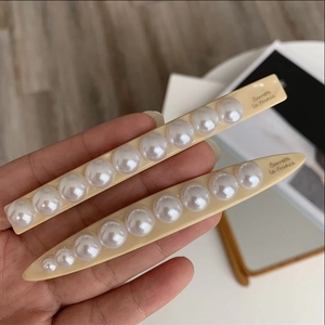 Detailed view of cream resin hair clips with white pearls and Barrette la France text