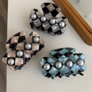 Three checkerboard acetate hair claws with pearls in grey, brown, and blue colors