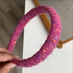 Detailed texture of a purple knitted rainbow headband with colorful fiber speckles
