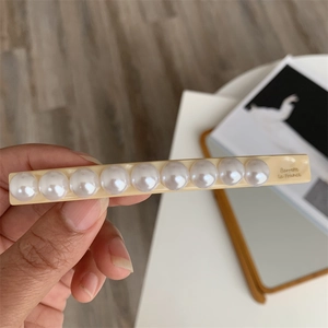 Detail of cream acrylic hair claw clip with faux pearls and Barrette La France text