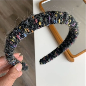 Detailed view of a thick knitted headband with colorful wool pom poms and soft fuzzy texture