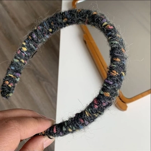 Detail shot of hand holding grey tweed knitted headband with colorful woven yarn texture