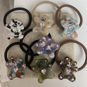 Close-up of seven cartoon bear hair ties with heart rhinestones on a stone tray