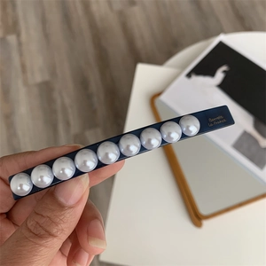 Detail showing deep blue hair barrette with nine white pearls and golden lettering