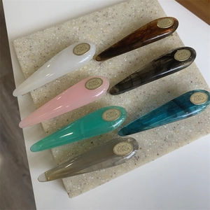 Detailed view of colorful acetate resin waterdrop hair clips with golden oval metal logo