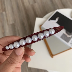 Macro detail of elegant burgundy resin barrette with gradient faux pearls and gold text