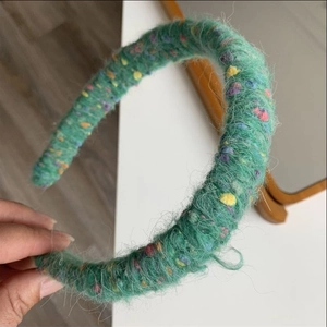 Detailed close-up of green wool knitted headband with colorful polka dots and fuzzy texture
