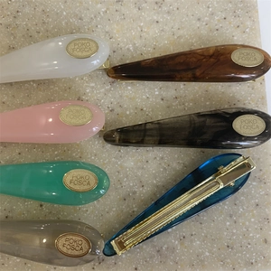 Detail view of colorful acrylic teardrop hair clips with secure gold metal duckbill clips