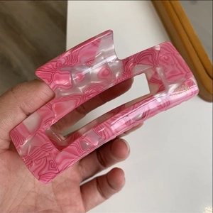Detail of pink and white marble texture acetate hair claw with golden handmade lettering