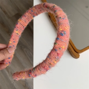 Detail of a handmade pink wool knitted headband with colorful yarn and soft texture