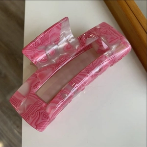 Detailed close-up of handmade resin hair claw clip with pink and white marble texture patterns