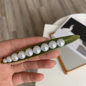 Close-up of green pea pod hair clip with elegant pearls and Barrette La France gold text