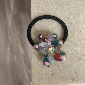 Detailed shot of cute bear hair tie with colorful terrazzo pattern and heart rhinestone