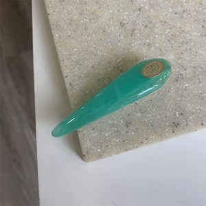 Detailed close-up of mint green marble pattern acrylic hair clip with a golden logo