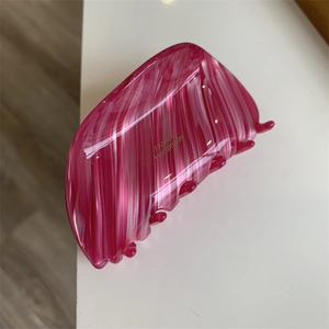 Close-up of pink marbled resin hair claw clip with golden France Handmade lettering