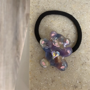 Close-up of cute marble resin bear hair tie with colorful heart rhinestone accent