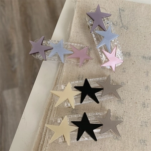 Detail showing colorful star hair clips on beige textured fabric and wooden background