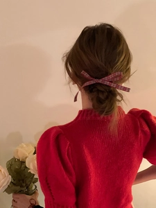 Detail of red plaid bow hair scrunchie styled on a brunette ponytail hair bun