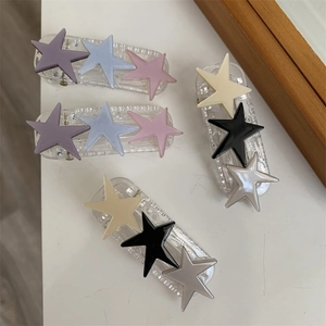 Detail view of colorful pentagram star hair clips with matte texture on white table