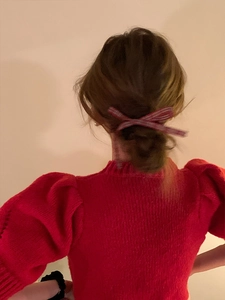 Detailed view of red and white plaid bow hairclip styled on a low bun hairstyle