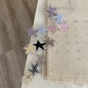 Close-up of matte star hair clips on acrylic base with pastel colors on burlap