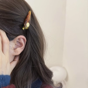 Elegant amber acetate drop hair clip with gold metal accent on woman's hair