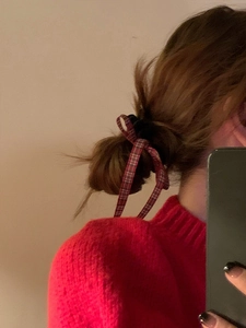 Macro detail of red plaid bow hair tie worn on a hair bun with long ribbons