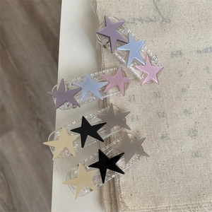 Detail view of four colorful star hair clips on a soft textured linen background