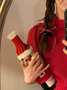 Close-up of a festive knitted Santa wine bottle cover with a striped hat and belt detail