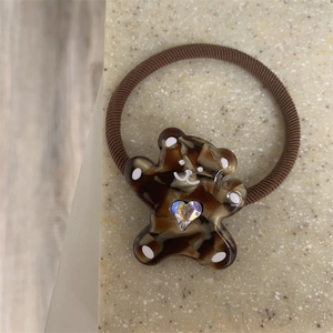 Close-up of brown elastic hair tie with a tortoiseshell bear and holographic heart crystal