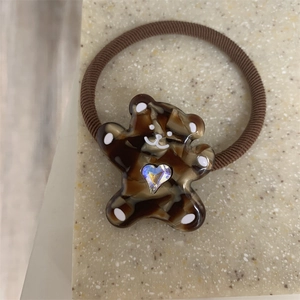 Detail of amber bear charm with heart crystal on elastic brown braided hair tie