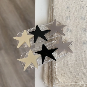 Detail of two hair clips with star charms on textured beige fabric background